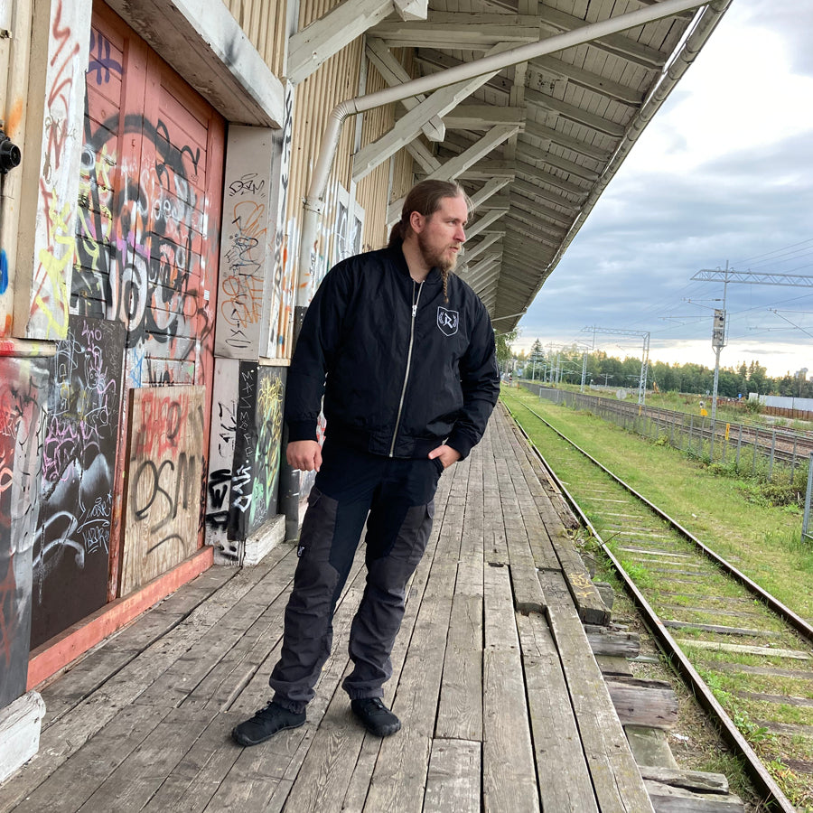 Rurik Fightgear-lentäjänpusakka.
Rurik FG "R" -logo rintapielessä sekä riimulogo selässä monivärisesti brodeerattuna. Kuvassa pilottitakki  Mikan päällä. ptcombet.com